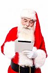 Old Aged Santa Using Touchscreen Pad Stock Photo