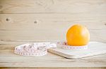 Orange And Measuring Tape On Wooden Background Stock Photo