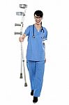 Orthopedic Doctor Walking Towards Camera With Crutches In Hand Stock Photo