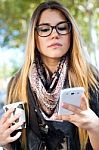 Portrait Of Beautiful Girl Drinking Coffee And Using Her Mobile Stock Photo