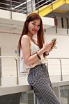 Portrait Of Thai Adult Beautiful Girl Using Her Smart Phone And Smile Stock Photo