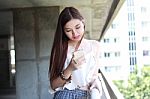 Portrait Of Thai Adult Beautiful Girl Using Her Smart Phone And Smile Stock Photo