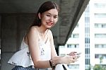 Portrait Of Thai Adult Beautiful Girl Using Her Smart Phone And Smile Stock Photo