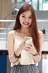 Portrait Of Thai Adult Beautiful Girl Using Her Smart Phone And Smile Stock Photo