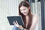 Portrait Of Thai Adult Beautiful Girl Using Her Tablet And Smile In University Stock Photo