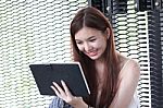 Portrait Of Thai Adult Beautiful Girl Using Her Tablet And Smile In University Stock Photo