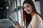 Portrait Of Thai Adult Beautiful Girl Using Her Tablet And Smile In University Stock Photo