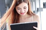 Portrait Of Thai Adult Beautiful Girl Using Her Tablet And Smile In University Stock Photo