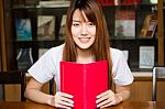 Portrait Of Thai Adult Student University Uniform Beautiful Girl Reading Red Book Stock Photo