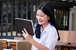 Portrait Of Thai High School Student Uniform Beautiful Girl Using Her Tablet Stock Photo