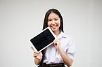 Portrait Of Thai High School Student Uniform Beautiful Girl Using Her Tablet Stock Photo