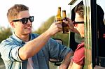 Portrait Of Two Friends Toasting With Bottles Of Beer In Car Stock Photo