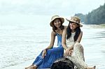 Portrait Of Young Beautiful Asian Tan Skin Woman Wearing Fashion Straw Hat Sitting On Wood Lock At Sea Beach With Relaxing Emotion Stock Photo