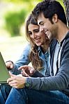 Portrait Of Young Couple At The Park Using A Laptop Stock Photo