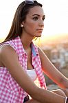 Pretty Girl Sitting On The Roof At Sunset Stock Photo