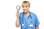 Pretty Physician Looking Through Magnifying Glass Stock Photo