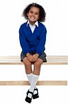 Pretty School Girl Seated Comfortably On A Bench Stock Photo