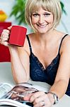 Pretty Woman With A Coffee Mug In Hand Reading Magazine Stock Photo