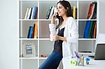 Pretty Young Woman Using Her Mobile Phone In The Office Stock Photo