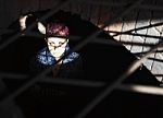 Punk Girl Sitting On The Floor Behind Metal Bars Stock Photo