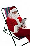 Relaxed Male Santa Operating Tablet Device Stock Photo