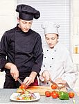 Senior Chef Teaches Young Chef To Cut Stock Photo