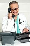 Senior Doctor Talking Over Phone Stock Photo