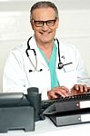 Senior Doctor Typing On Keyboard Stock Photo