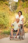 Senior Woman Pushing Her Disabled Hasband On Wheelchair Stock Photo