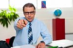 Serious Manager Pointing At You From His Work Desk Stock Photo