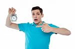 Shocked Young Guy Holding Alarm Clock Stock Photo