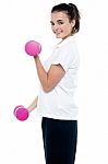 Side Pose Of Girl With Dumbbells Working Out Stock Photo