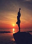 Silhouette Yoga Girl By The Beach At Sunrise Stock Photo