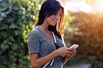 Smiling Beautiful Woman Texting With Her Phone In The Garden Stock Photo