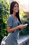 Smiling Beautiful Woman Texting With Her Phone In The Garden Stock Photo