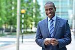 Smiling Businessman Holding Smartphone Stock Photo