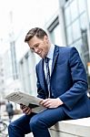 Smiling Businessman Reading Paper At Outdoors Stock Photo