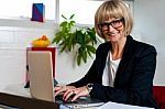 Smiling Female Manager Typing Report On Laptop Stock Photo