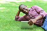 Smiling Man Lying On The Lawn With Tablet Stock Photo