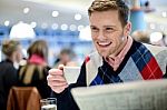 Smiling Man Reading Newspaper At Restaurant Stock Photo