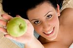 Smiling Woman Offering Apple On An Isolated Background Stock Photo