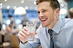 Smiling Young Man Drinking Water In Cafe Stock Photo