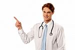 Smiling Young Physician Pointing Away Stock Photo