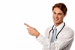 Smiling Young Physician Pointing Away Stock Photo