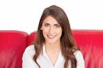 Smiling Young Woman With Brown Hair Sitting On Sofa Stock Photo