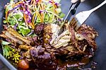 Steak Knife And Fork Slicing Grilled Rib Eye Beef Steak With Vegetable Salad In Black Bowl Stock Photo