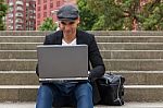 Student Working On His Laptop With An Irish Cap Stock Photo