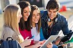 Students Having Fun With Smartphones And Tablets After Class Stock Photo