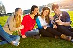 Students Having Fun With Smartphones And Tablets After Class Stock Photo