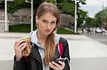 Teenager Eating Cake Looking In Phone Stock Photo